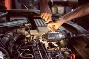 5 Reasons to Specialize in Diesel Truck and European Auto Repair ; AutoFix Auto Shop Coaching; auto mechanic working on a diesel car engine with a repair flashlight sitting on engine