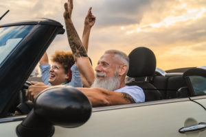 Retirement Planning for Auto Repair Shop Owners with Chris Cotton and AutoFix Auto Shop Coaching; image of older couple happy driving with their hands up driving convertible car