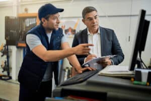 Expert guidance on financial planning from AutoFix Auto Repair Shop Coaching. Image of a business coach and a protege discussing financial planning and operational streamlining.