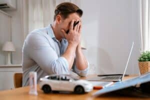 Experts in Auto Repair Shop Consulting from AutoFix Auto Repair Shop Coaching. Image of a stressed auto shop owner putting his hand to his face after discovering a flaw in his automotive business while trying to find a solution.