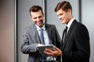Two young business managers in professional attire are engaged in a discussion while looking at a tablet. Auto Shop Coaching pledge for dressing to impress