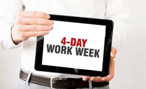 4-Day Work Week for Auto Repair Shops by AutoFix-Auto Shop Coaching. A person holding a tablet displaying the text "4-DAY WORK WEEK," highlighting the benefits of a shorter work week for improved employee morale, productivity, and customer satisfaction in auto repair shops.