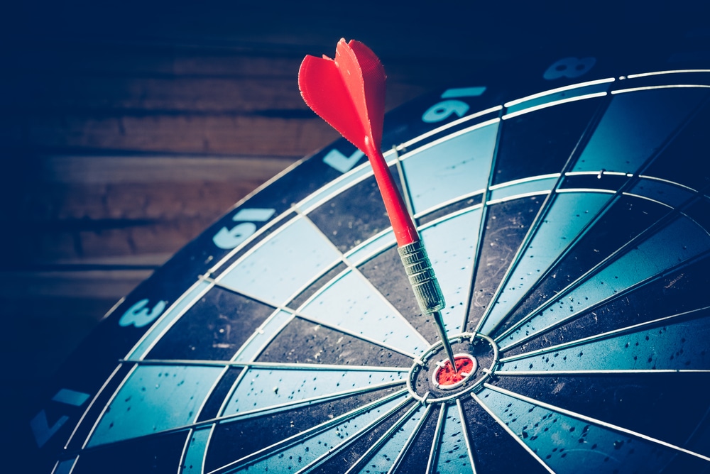 Goal setting by AutoFix- Auto Shop Coaching. A dart hitting the bullseye on a dartboard, symbolizing setting clear, fixed goals and achieving them consistently, illustrating the importance of commitment and focus for success in business and personal life.