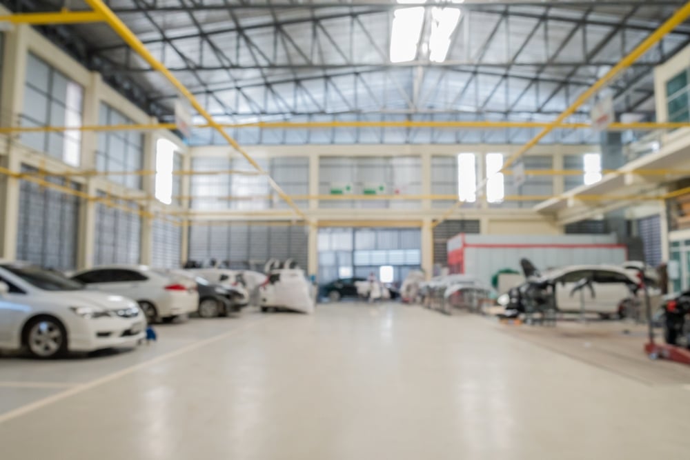 Elevate your auto repair shop by AutoFix Auto Shop Coaching. Image of a large, well-lit auto repair facility filled with cars undergoing maintenance, illustrating the scale and professionalism of operations at AutoFix Auto Shop Coaching.