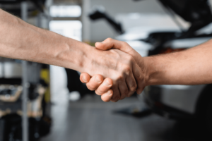 auto repair shop business coaching, Auto Shop Coaching, United States, Auto Shop Coaching. A handshake between two individuals in an auto repair shop.