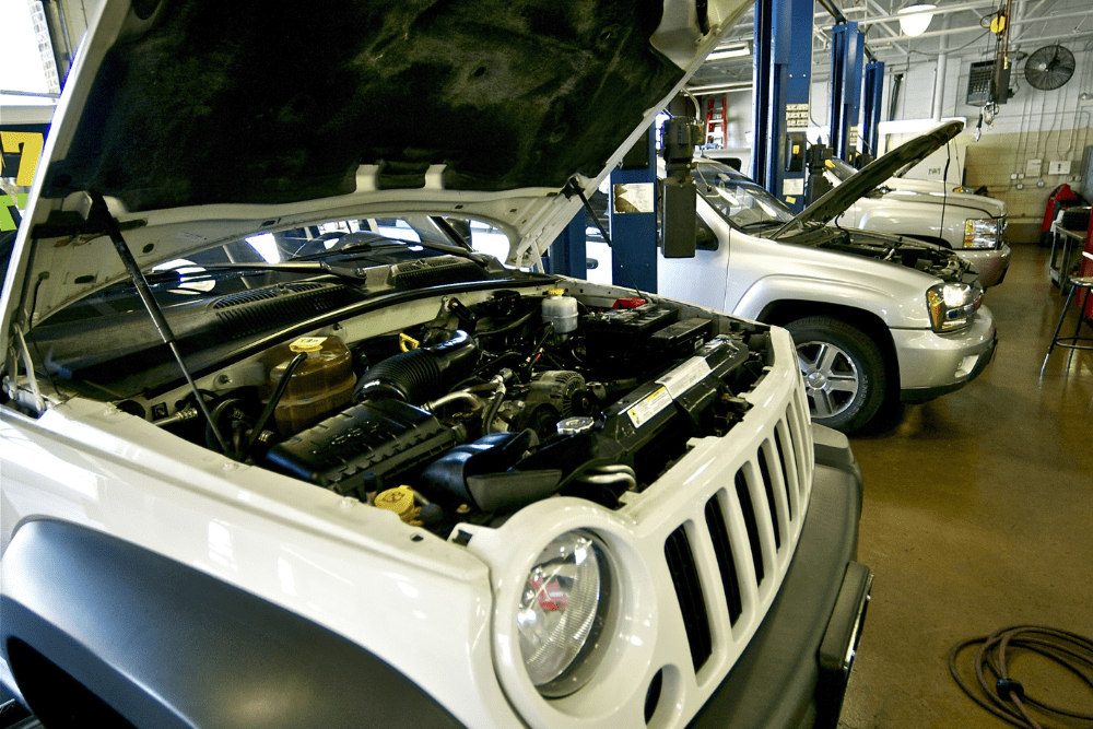 Auto repair shop coaching in 2025 by AutoFix. Image of open vehicle hoods and hydraulic lifts inside a bright, organized repair shop.