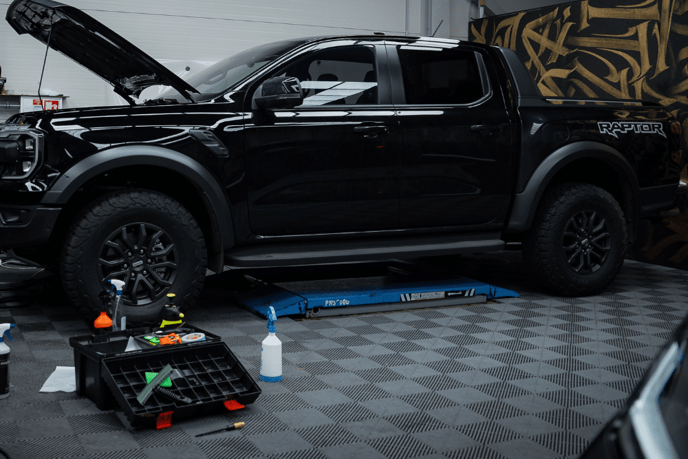diesel repair shop coaching by AutoFix Auto Shop Coaching. Ford Raptor undergoing maintenance in a clean auto repair shop, with the hood open and tools and cleaning supplies organized nearby.