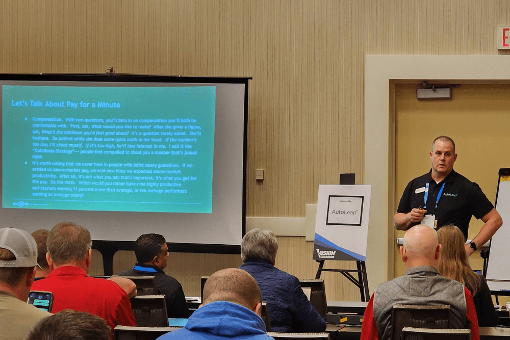 Auto repair labor rate, auto repair shop coaching by AutoFix Auto Shop Coaching. Image of Chris Cotton speaking to shop owners in a training session, emphasizing growth, leadership, pay, and performance improvement.