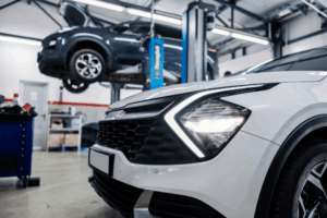 Auto repair shop, auto shop coaching by AutoFix Auto Shop Coaching. Image of a modern SUV in a repair bay with another vehicle lifted in the background, showcasing a professional shop environment focused on high-quality automotive maintenance and diagnostics.