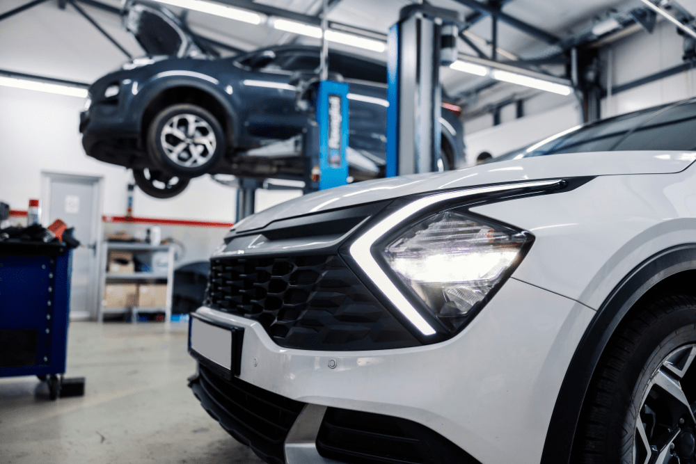 Auto repair shop, auto shop coaching by AutoFix Auto Shop Coaching. Image of a modern SUV in a repair bay with another vehicle lifted in the background, showcasing a professional shop environment focused on high-quality automotive maintenance and diagnostics.