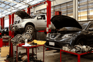 Auto repair shop, auto shop coaching by AutoFix Auto Shop Coaching. Image of multiple vehicles on lifts with hoods open while technicians perform diagnostics and engine repairs, highlighting comprehensive automotive maintenance, engine work, and multi-vehicle service capabilities in a modern auto repair facility.