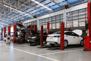 Auto repair shop cash flow problems, auto shop coaching at AutoFix Auto Shop Coaching. Image of multiple vehicles positioned on service lifts inside a large automotive repair facility.